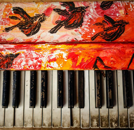 Picture of an old piano keyboard with colorful birds painted on it